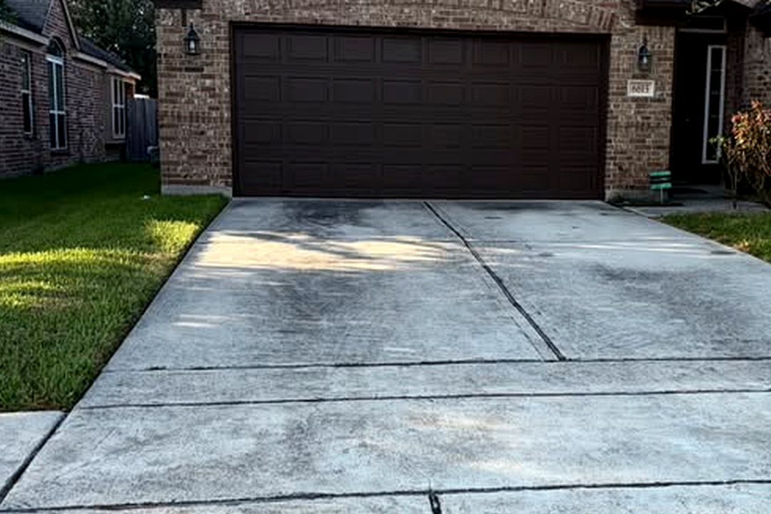 The same Houston driveway before pressure washing, stained with dirt and mildew