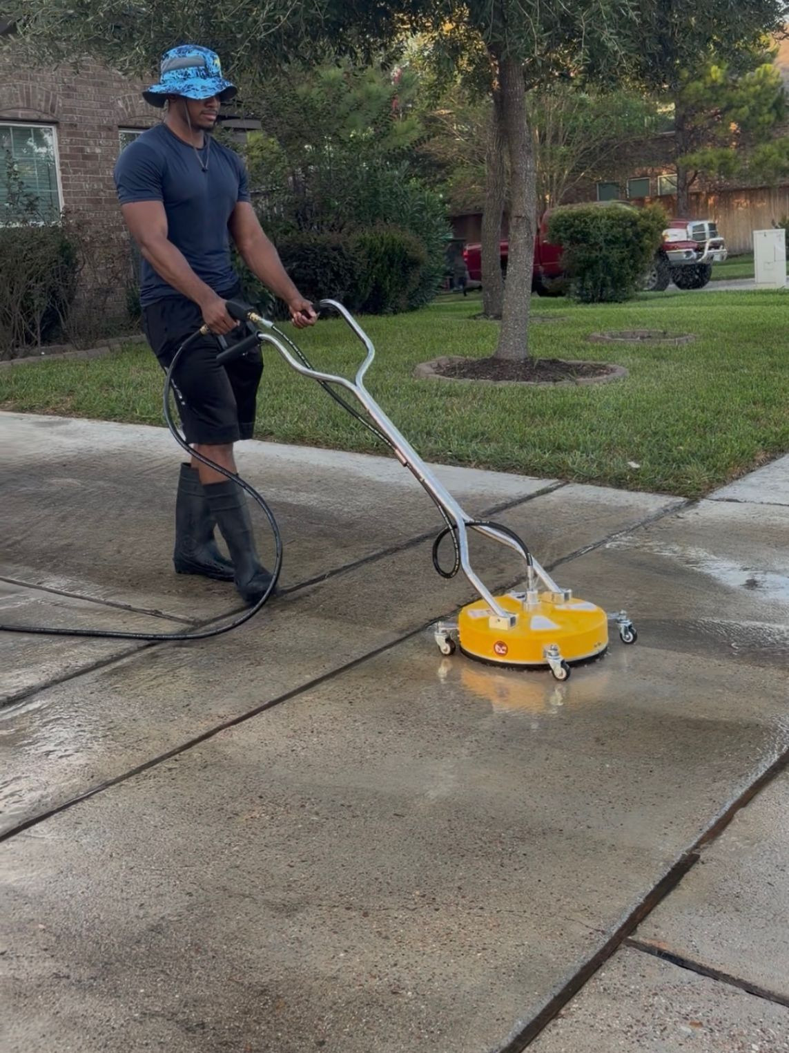Texas Muscle Wash owner running a surface cleaner across a Houston driveway